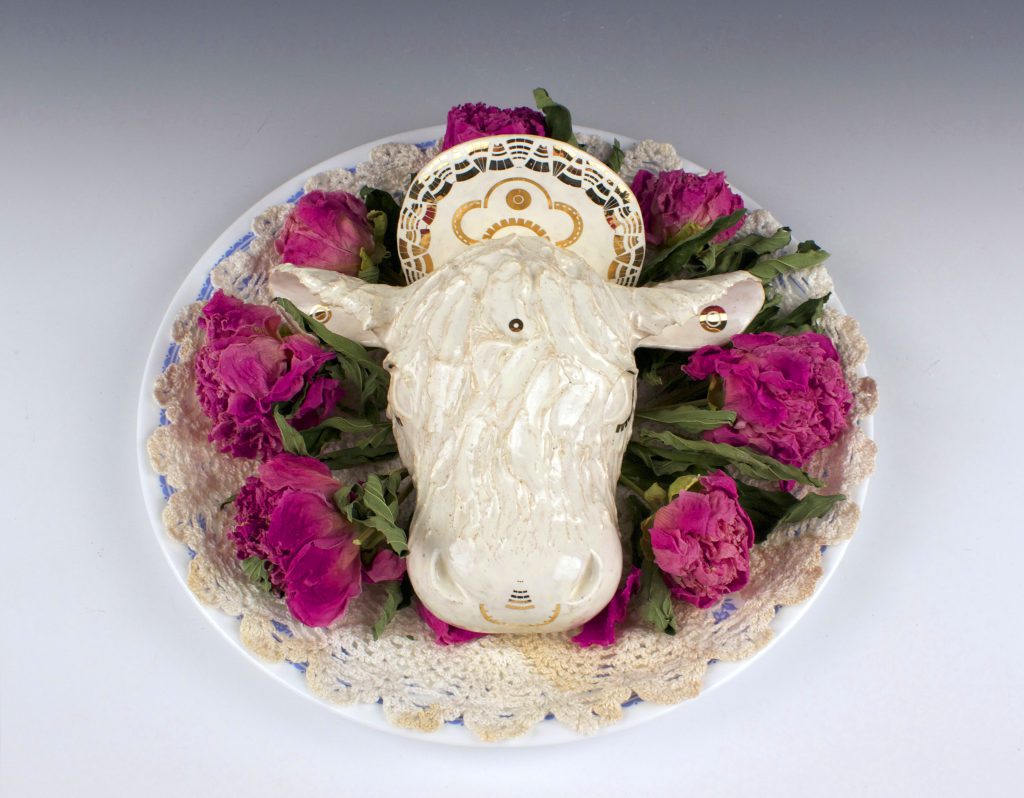student ceramic work of sacred cow head on plate of flowers