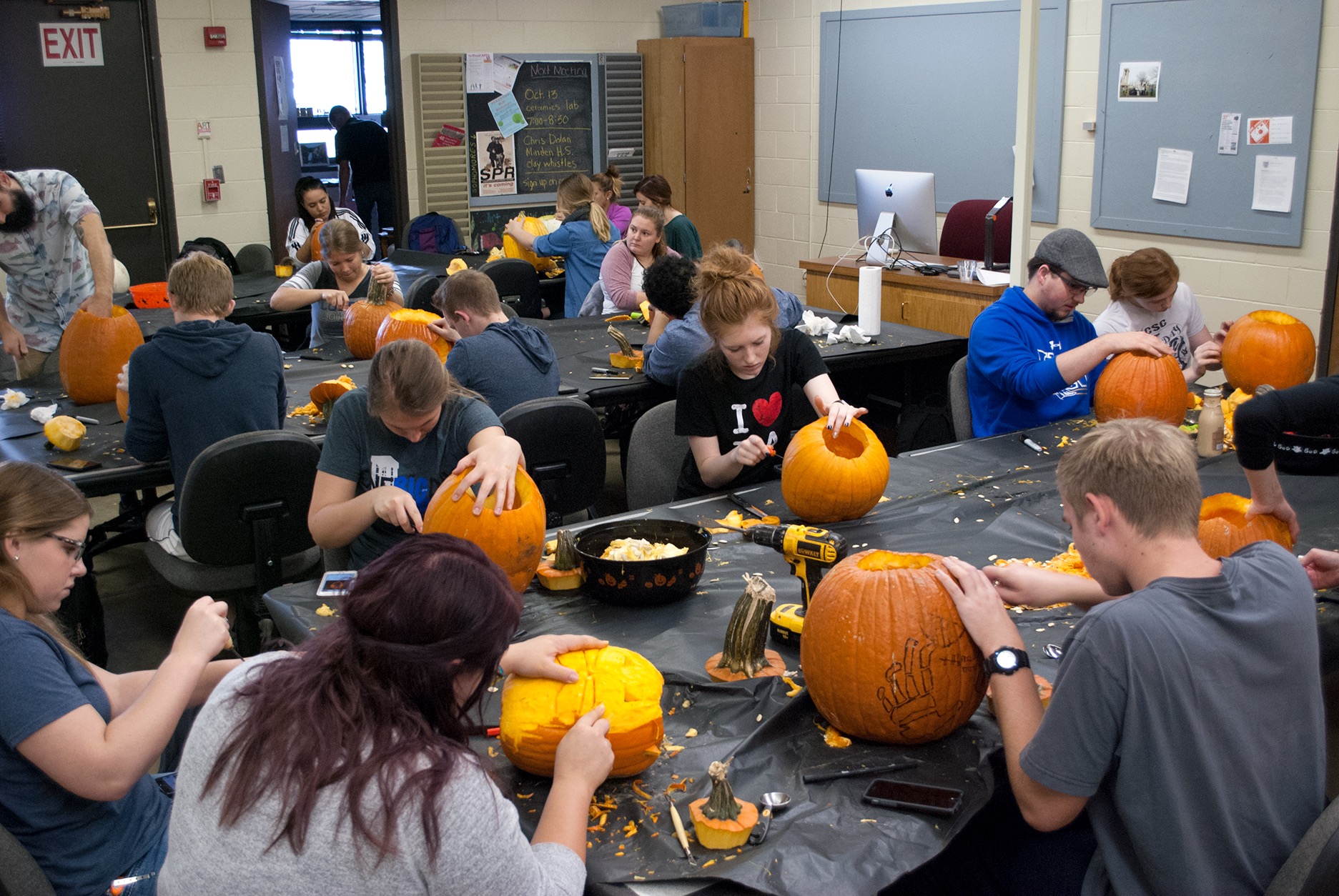 students carving pumpkin for UNK Art's pumpkin carving contest
